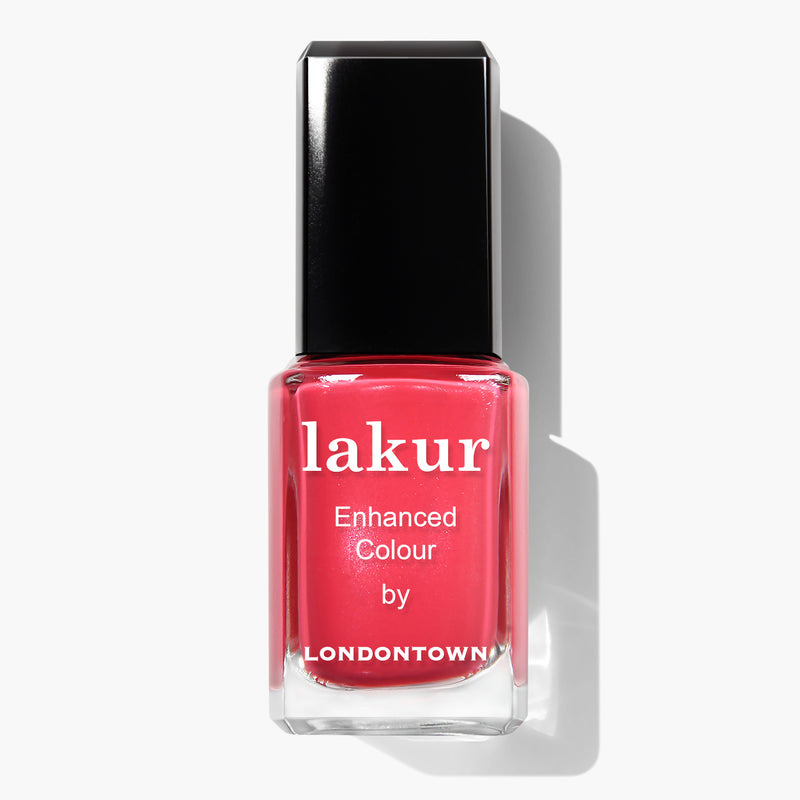 A bottle of Lakur Enhanced Colour nail polish by LONDONTOWN called "Weekend Cheers" in a coral pink crème shade with a black cap, shown against a white background. This vegan, cruelty-free nail polish offers vibrant color with every swipe.