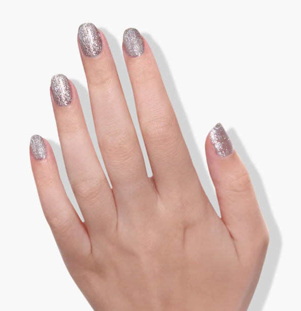 A hand with glittery silver nail polish on all fingers, displayed against a white background, showcasing the flawless wear of LONDONTOWN's Tiara UV/LED Gel Color with its self-leveling formula.